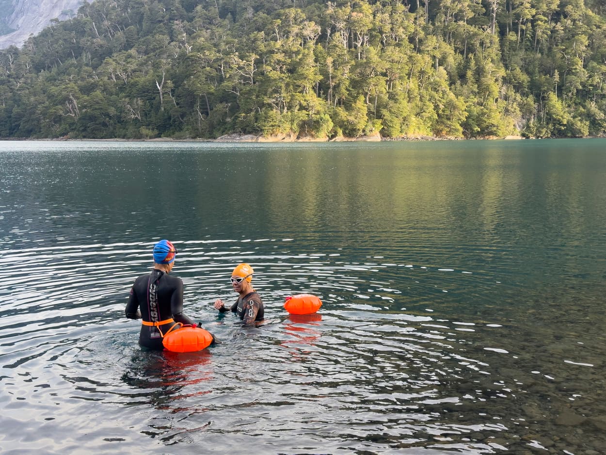 Nadador cruzando el lago Nahuel Huapi con la cordillera de fondo