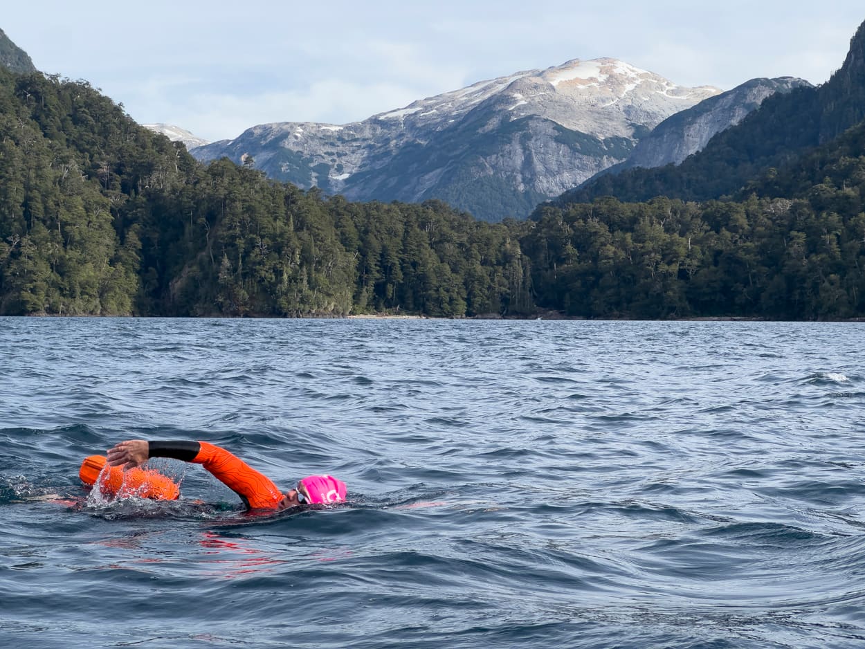 Nadador en pleno cruce del lago, con las montañas detrás