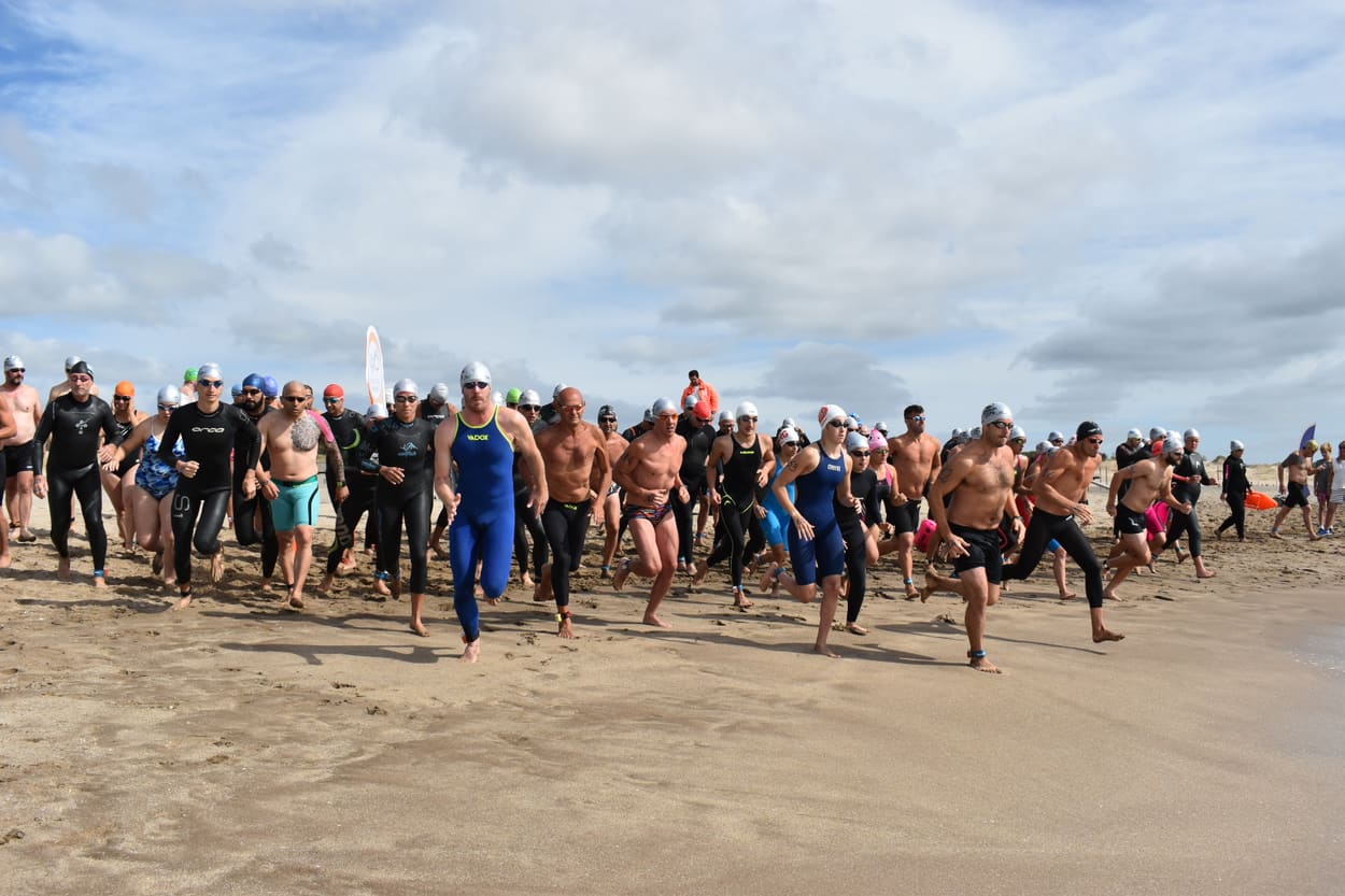 Nadadores corriendo hacia el mar en la largada, en la playa de Pinamar