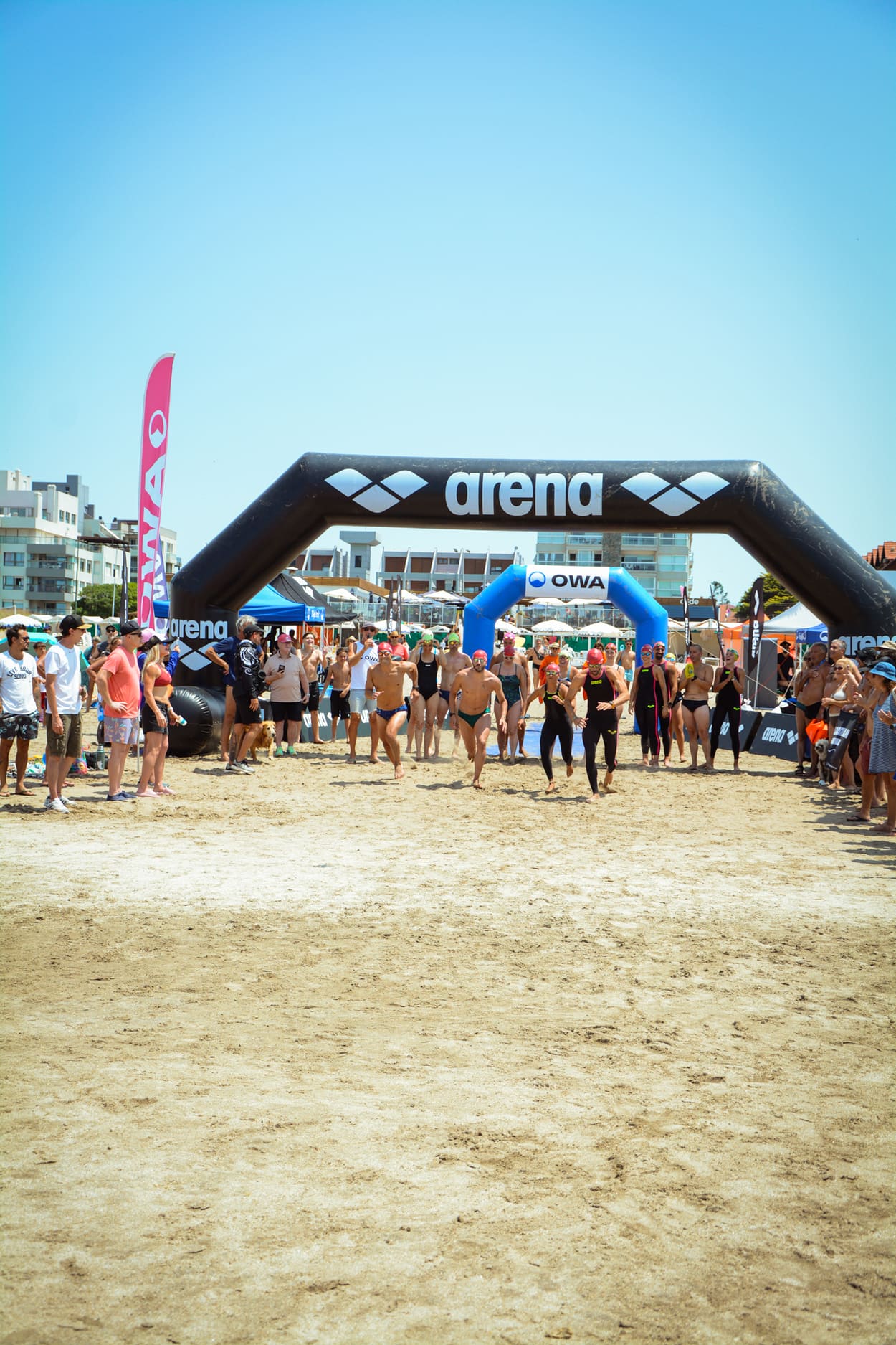 Nadadores saliendo a correr bajo el arco de arena y OWA en la playa